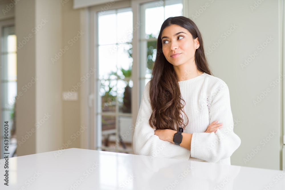 Young beautiful woman at home on white table smiling looking side and staring away thinking.