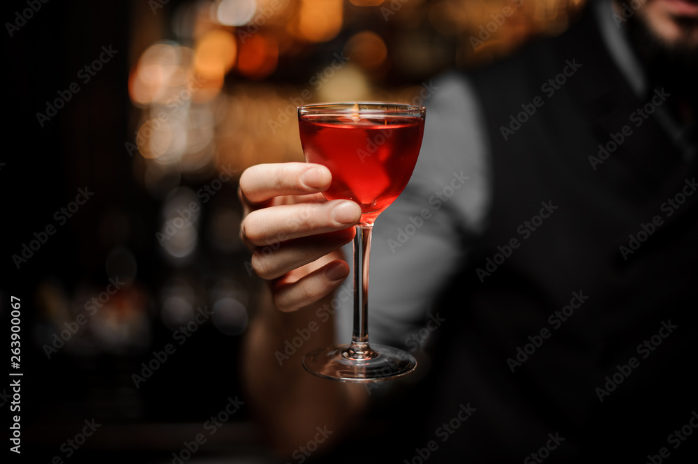 Close-up of an alcohol cocktail with orange rind in bartender's hand