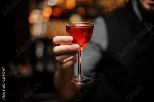 Close-up of an alcohol cocktail with orange rind in bartender's hand