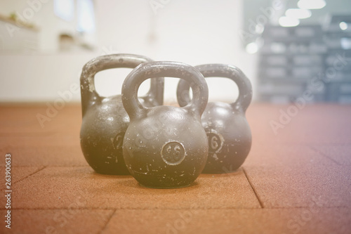 Тhree black iron kettlebells with markings 24 and 16 kg standing close to each other. Gym and fitness equipment. Workout tools