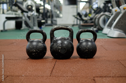 Fototapeta Naklejka Na Ścianę i Meble -  Тhree black iron kettlebells with markings 24 and 16 kg standing close to each other. Gym and fitness equipment. Workout tools