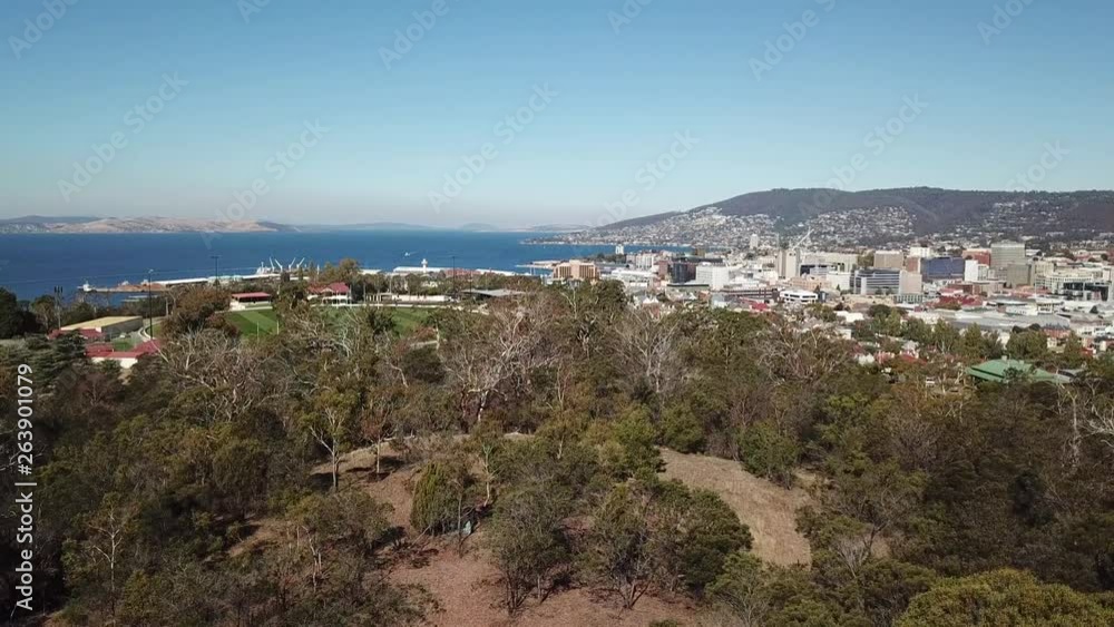 Aerial pan up over trees to reveal seaside port and city of Hobart, Tasmania, Australia Aerial pan up over trees to reveal seaside port and city of Hobart, Tasmania, Australia