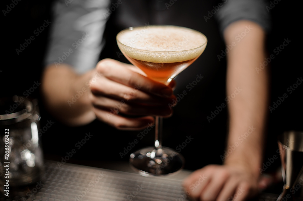 Close-up of bartender holding cocktail with foam