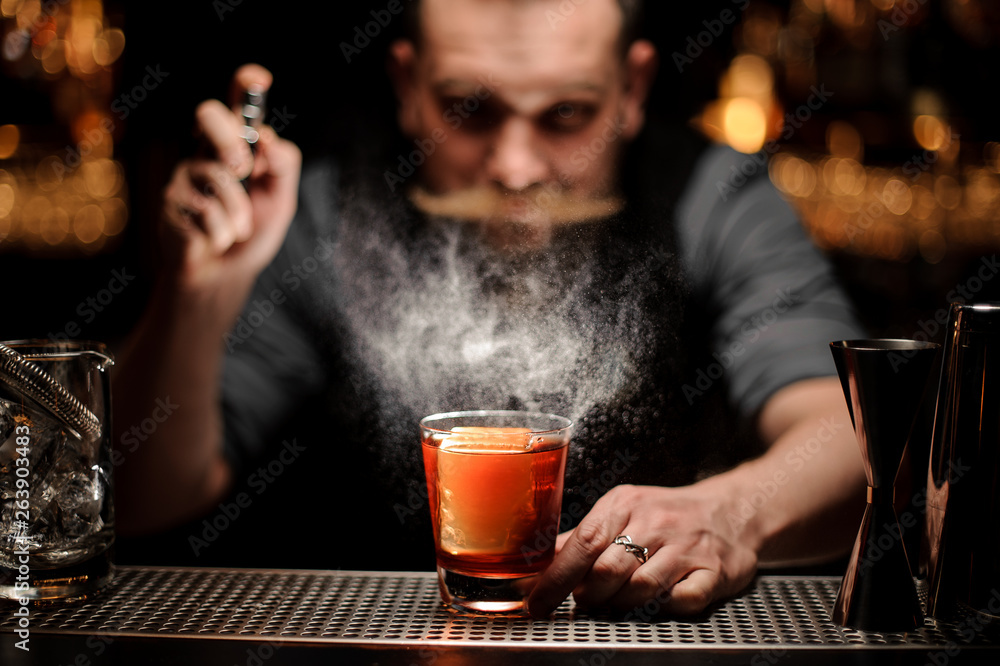 Brutal bartender pours an alcohol cocktail using sprayer