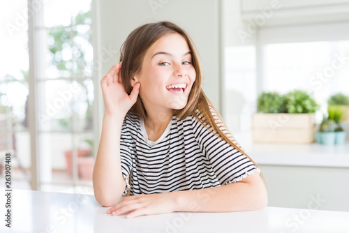 Beautiful young girl kid wearing stripes t-shirt smiling with hand over ear listening an hearing to rumor or gossip. Deafness concept. Free Download Beautiful young girl kid wearing stripes t-shirt smiling with hand over ear listening an hearing to rumor or gossip. Deafness concept. - GFXLoad