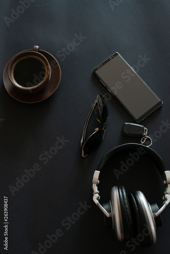 cup of coffee, sun glasses, smartphone, headphones on a black background