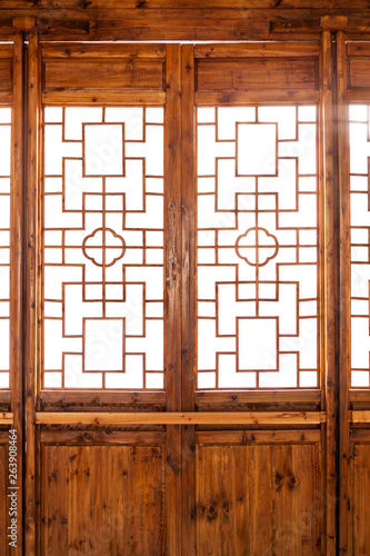 Closeup Chinese old wooden frame door with decorative pattern under the sunshine ,view from inside of building.