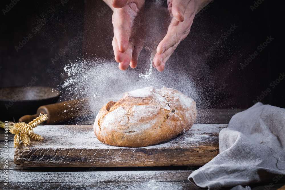 Obraz premium Baker cooking bread. Man slaps flour over the dough. Man's hands Making bread