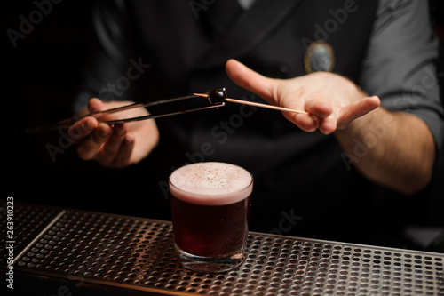 Bartender putting cherry on a toothpick with forceps