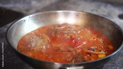Close up detailed view on hot steaming vegetable stew simmering in steel frying pan