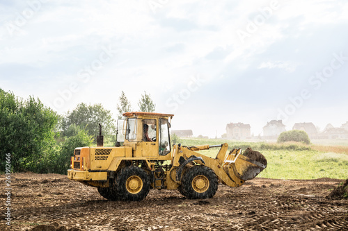 large yellow wheel loader aligns a piece of land for a new building