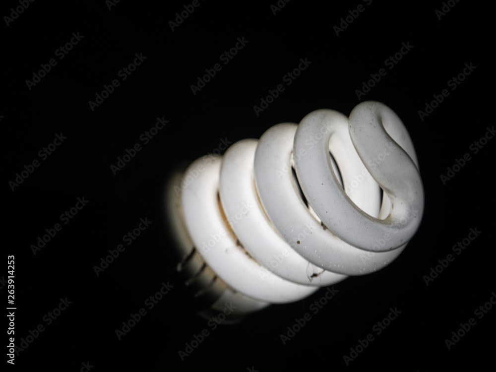 A white energy saving bulb and blacked background. A white energy saving bulb and blacked background.