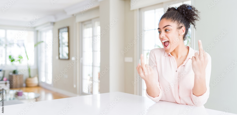 Wide angle of beautiful african american woman with afro hair Showing middle finger doing fuck you bad expression, provocation and rude attitude. Screaming excited