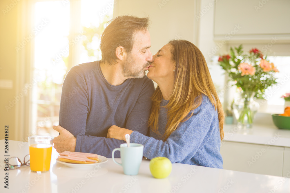 Beautiful romantic middle age couple kissing having healthy breaskfast in the morning at home