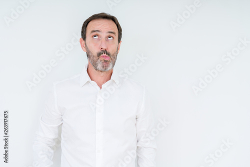 Elegant senior man over isolated background making fish face with lips, crazy and comical gesture. Funny expression.