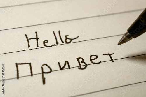 Beginner Russian language learner writing Hello word in Russian cyrillic alphabet on a notebook