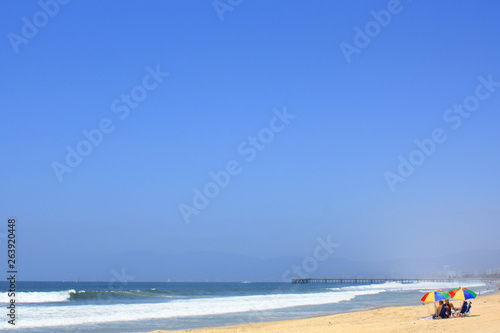 Tiny people in the distance on a bech under a clear, blue sky © Robin Keefe