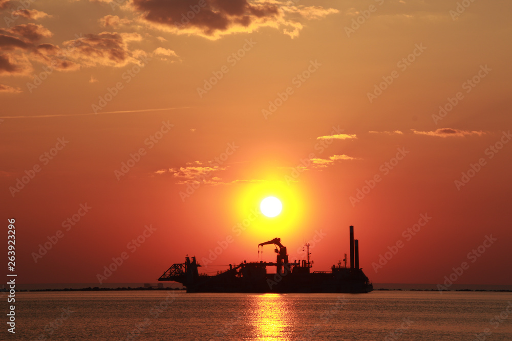 Silhouette of industrial ship and sunset over the sea
