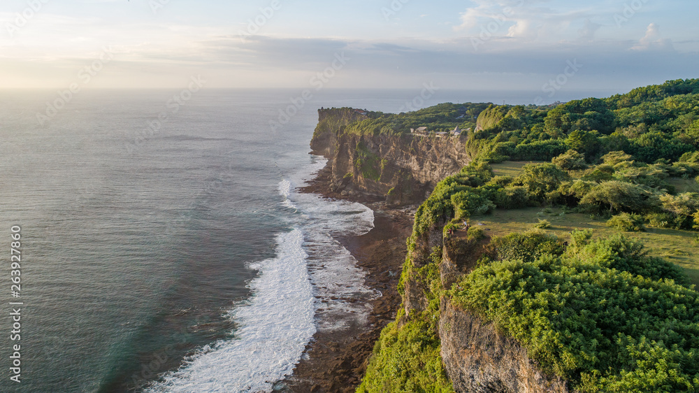 Stunning cliff view over the indian  ocean on a golden hour at the Uluwatu temple in Bali, Indonesia, agriculture green vegetation – high quality aerial image