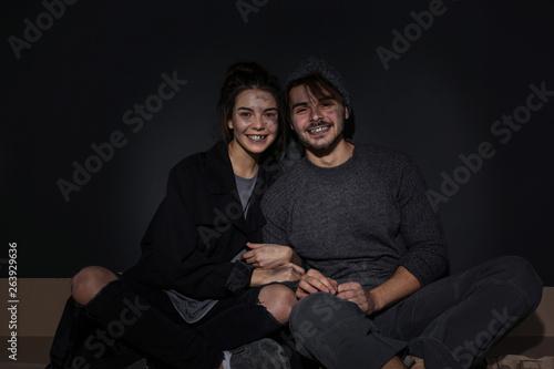 Slika na platnu Poor young couple sitting on floor near dark wall