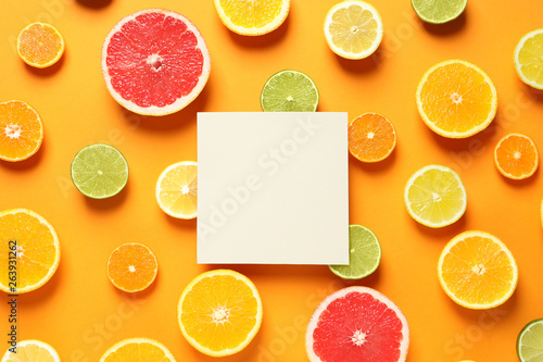 Fresh citrus fruits and blank card on color background, flat lay. Space for text