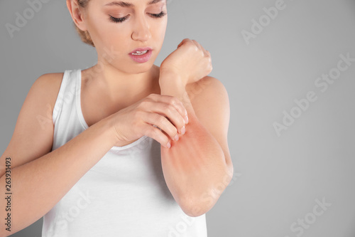 Foto Woman scratching forearm on grey background, space for text