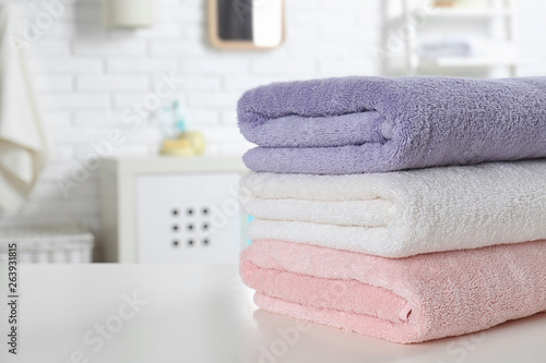 Stack of fresh towels on table in bathroom, closeup. Space for text
