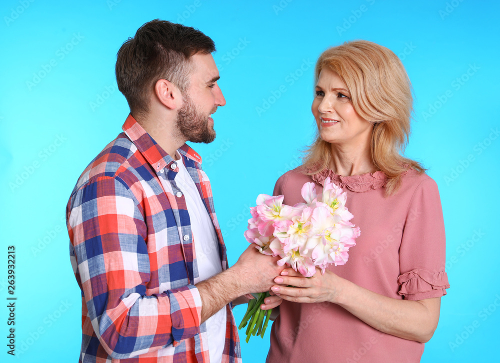 Young man congratulating his mature mom on color background. Happy Mother's Day Young man congratulating his mature mom on color background. Happy Mother's Day