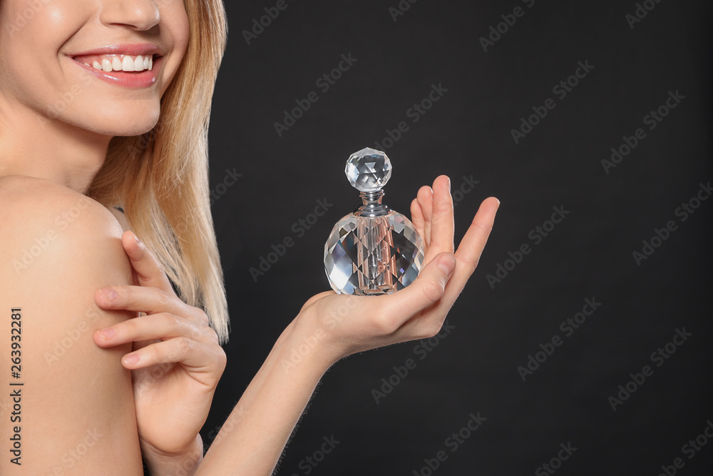 Young woman with bottle of perfume on black background, closeup Young woman with bottle of perfume on black background, closeup