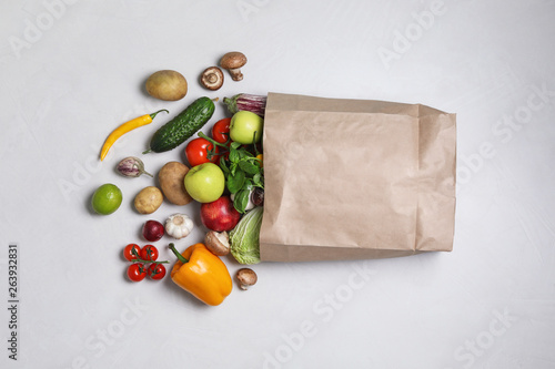 Fototapeta Naklejka Na Ścianę i Meble -  Paper bag with fresh vegetables and fruits on light background, flat lay