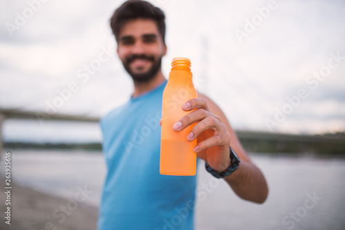 Take a break.Handsome fitness man holding water bottle