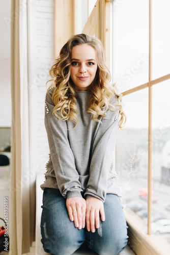 Free Download Beautiful young caucasian European woman sitting on windowsill looking straight - GFXLoad