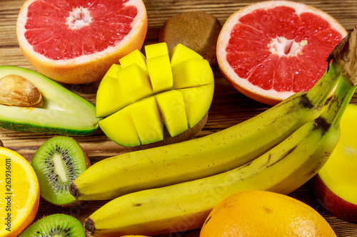 Assortment of tropical fruits on wooden table. Still life with bananas  mango  oranges  avocado  grapefruit and kiwi fruits
