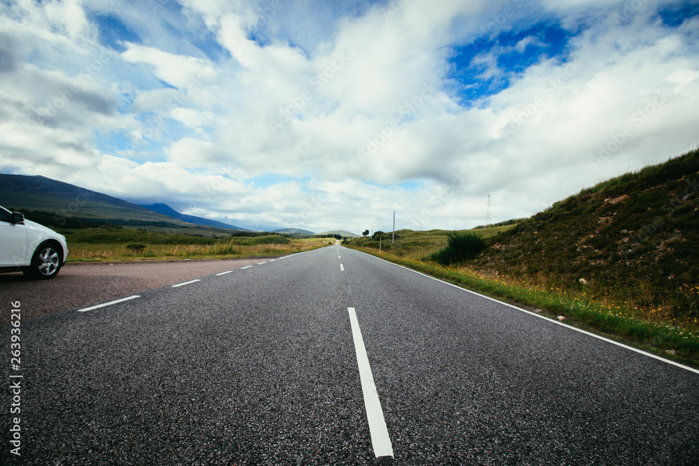 Trip or adventure: Abandoned, dramatic road in Scotland, cloudy sky.