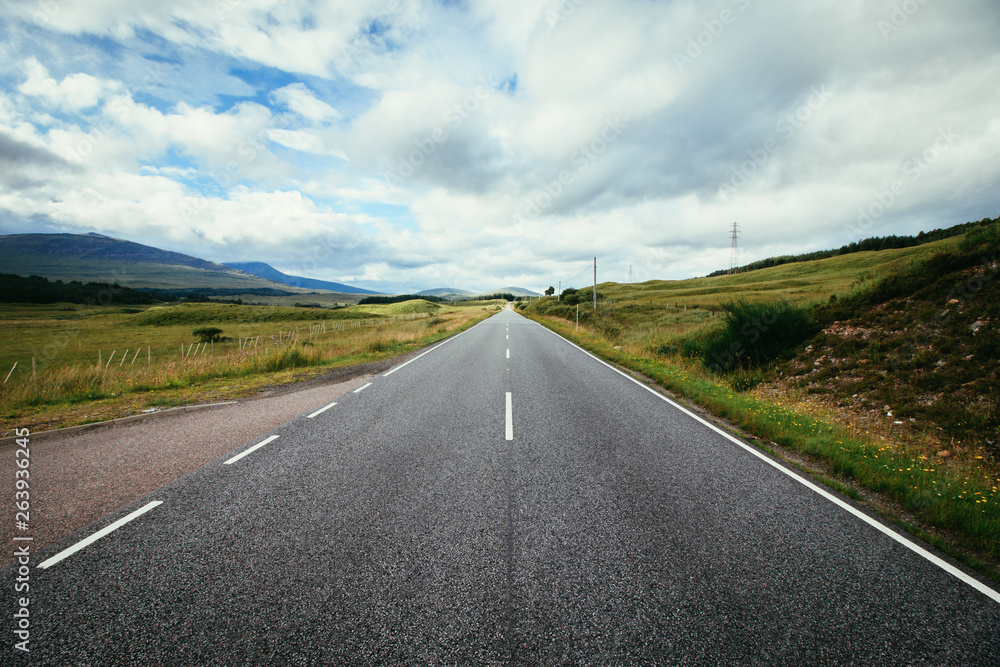 Trip or adventure: Abandoned, dramatic road in Scotland, cloudy sky.