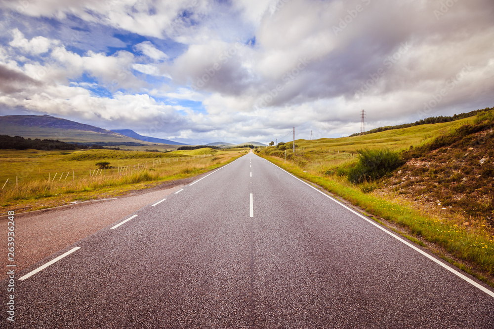 Trip or adventure: Abandoned, dramatic road in Scotland, cloudy sky.