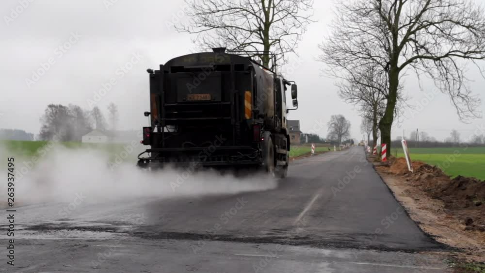 Truck spraying new asphalt with water. Bitumen emulsion. Road repair. Asphalt cooling. Preparation for paving. Oil spreader truck applying tack coats on a surface.