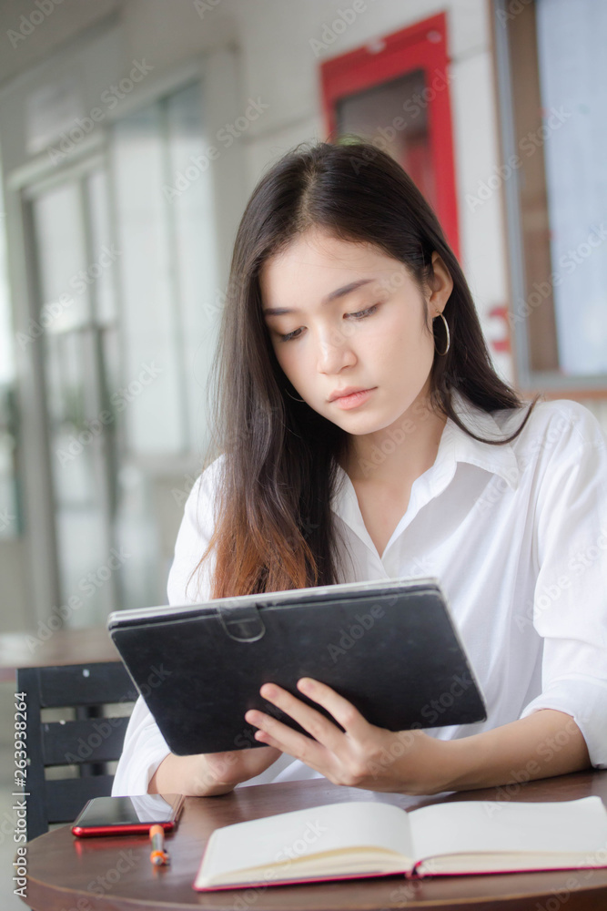 Portrait of thai adult student university uniform beautiful girl using her tablet.