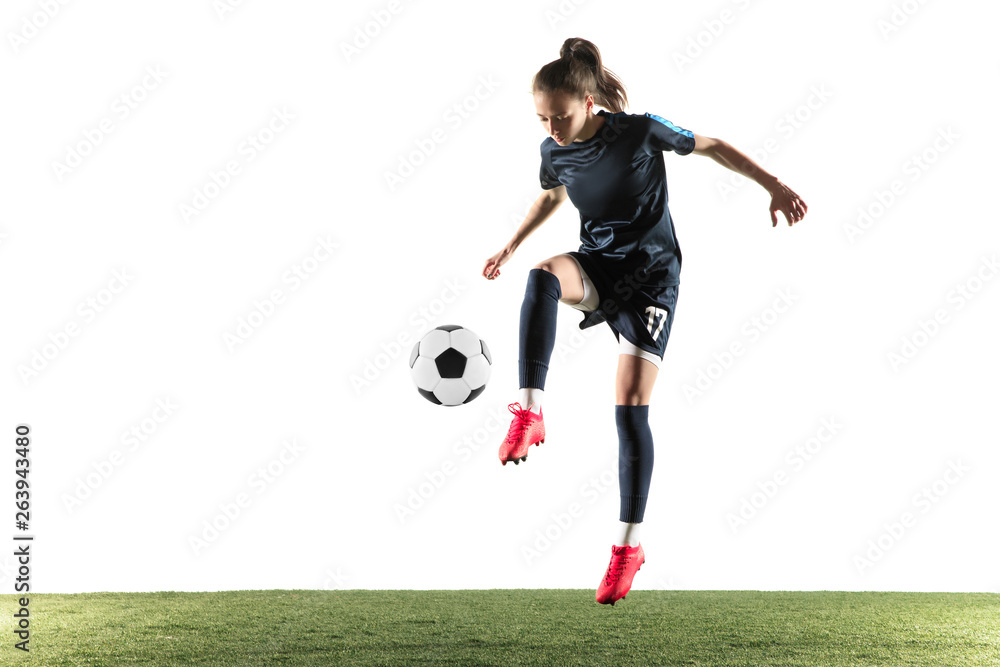 Female soccer player kicking ball isolated over white background