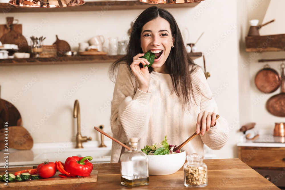 Image of caucasian brunette woman eating healthy green salad with vegetables at home