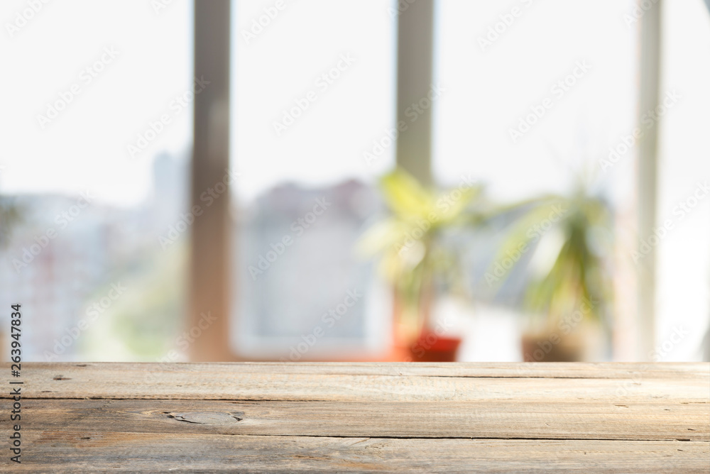 Wood table top on blur of window glass and abstract green from garden with city view in the morning background. For montage product display