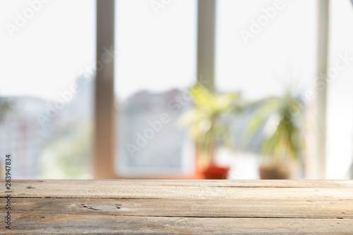 Wood table top on blur of window glass and abstract green from garden with city view in the morning background. For montage product display © kishivan