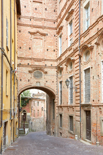 Empty street with red bricks building and arch in a summer day in Mondovi  Italy