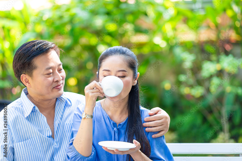 Asian aged couple drinking coffee in green park Asian aged couple drinking coffee in green park