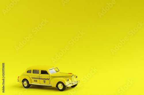 Old retro yellow toy car taxi on yellow background with copy space. Travel concept © IKvyatkovskaya