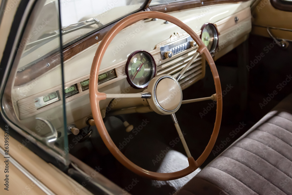View on opened window with the steering wheel and the interior of the old Russian retro vintage car of the executive class released in the Soviet Union beige View on opened window with the steering wheel and the interior of the old Russian retro vintage car of the executive class released in the Soviet Union beige