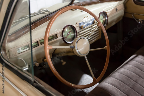 View on opened window with the steering wheel and the interior of the old Russian retro vintage car of the executive class released in the Soviet Union beige