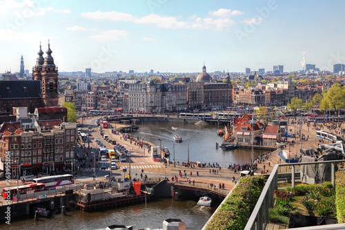 Amsterdam cityscape with Grand Amarath hotel. City streets with active tram and car traffic along the canal. Panoramic distance view. 