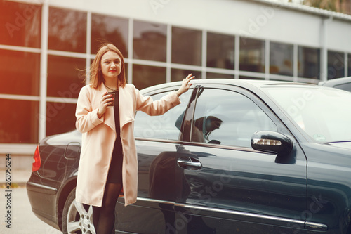 young and elegant business woman standing near car with coffee