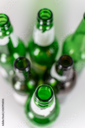 Top view of a pack of blurred  empty green and brownlongneck beer glass bottles, with ripped labels on a white background. Reuse, acoholism, recycle and party concept. Warm tones. photo